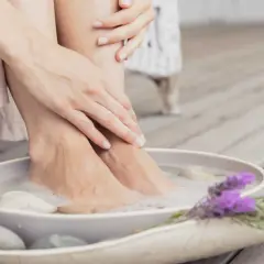 Détente avec un bain de pied maison, pieds dans l'eau savonneuse, galets et lavande.