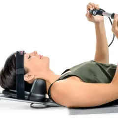 Une femme utilise un appareil pour la traction du cou, allongée sur le dos, avec un bandeau sur la tête.