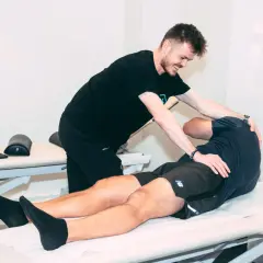 Un ostéopathe pratique un ostéo massage sur un patient allongé sur une table de soin, soulageant ses tensions musculaires.