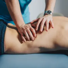Mains d'un thérapeute massant le dos d'un patient, soulageant un muscle froissé.