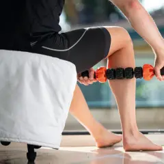 Un athlète utilise un rouleau de massage pour un massage de récupération sur sa jambe.