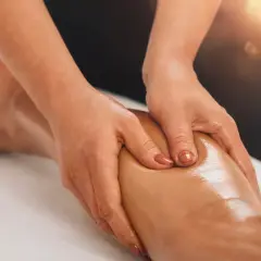 Mains massant un mollet huilé, profitant des bienfaits relaxants et décontractants pour soulager les tensions musculaires.