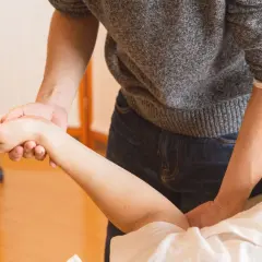 Mains expertes prodiguant un massage du bras pour améliorer la circulation sanguine.