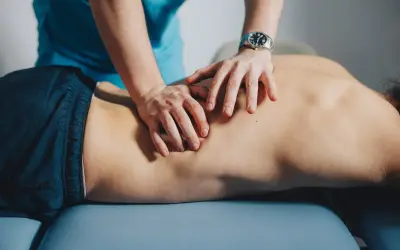 Mains d'un thérapeute massant le dos d'un patient, soulageant un muscle froissé.