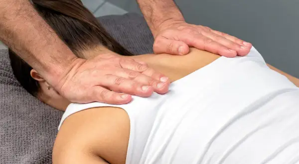 Mains d'un masseur travaillant sur le dos d'une femme, soulageant la tension musculaire.