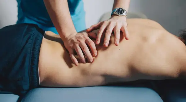 Mains d'un ostéopathe pratiquant un massage du dos sur un patient allongé.