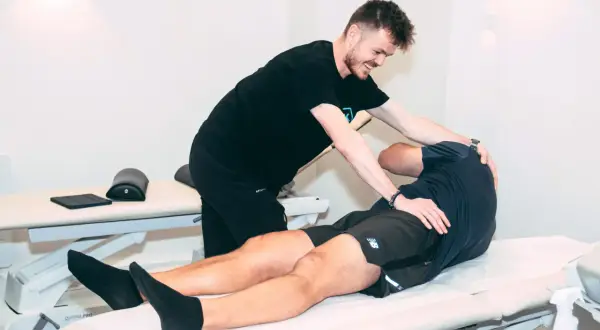 Un ostéopathe pratique un ostéo massage sur un patient allongé sur une table de soin, soulageant ses tensions musculaires.