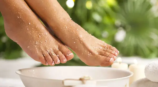 Pieds délicats recouverts de gros sel et de bicarbonate, prêts pour un bain de pied relaxant.