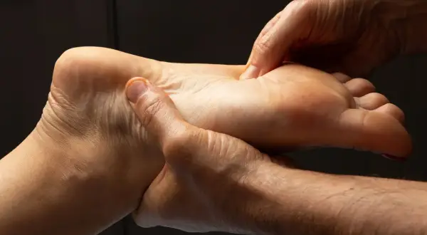 Mains massant la voûte plantaire, une séance de réflexologie plantaire pour soulager la sciatique.