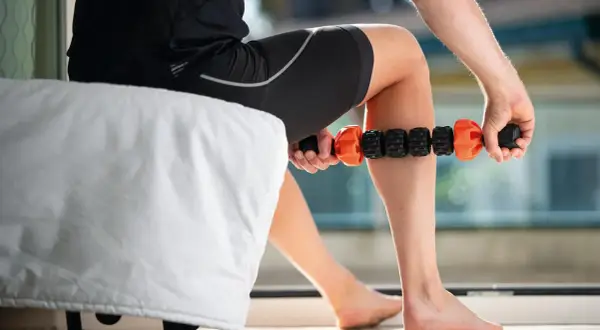 Un athlète utilise un rouleau de massage pour un massage de récupération sur sa jambe.