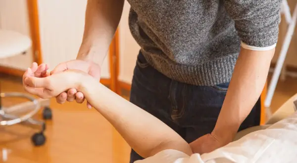 Mains expertes prodiguant un massage du bras pour améliorer la circulation sanguine.