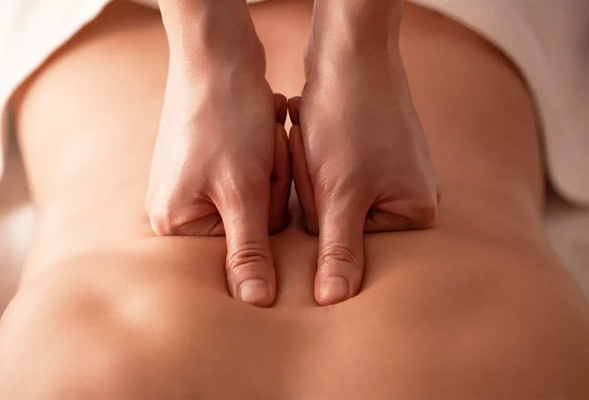 Mains expertes appliquant un massage profond sur le bas du dos pour soulager les tensions et favoriser la relaxation.