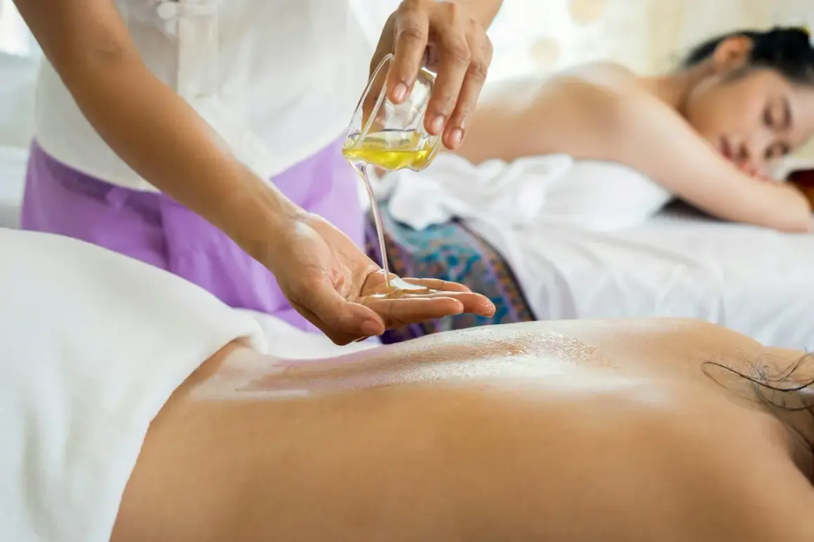 Un massage omoplate relaxant avec de l'huile chaude. Une autre femme se repose sur la table de massage en arrière-plan.