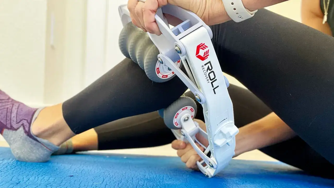 Une personne utilise un rouleau pour travailler les fascias de sa jambe, améliorant ainsi sa récupération musculaire.