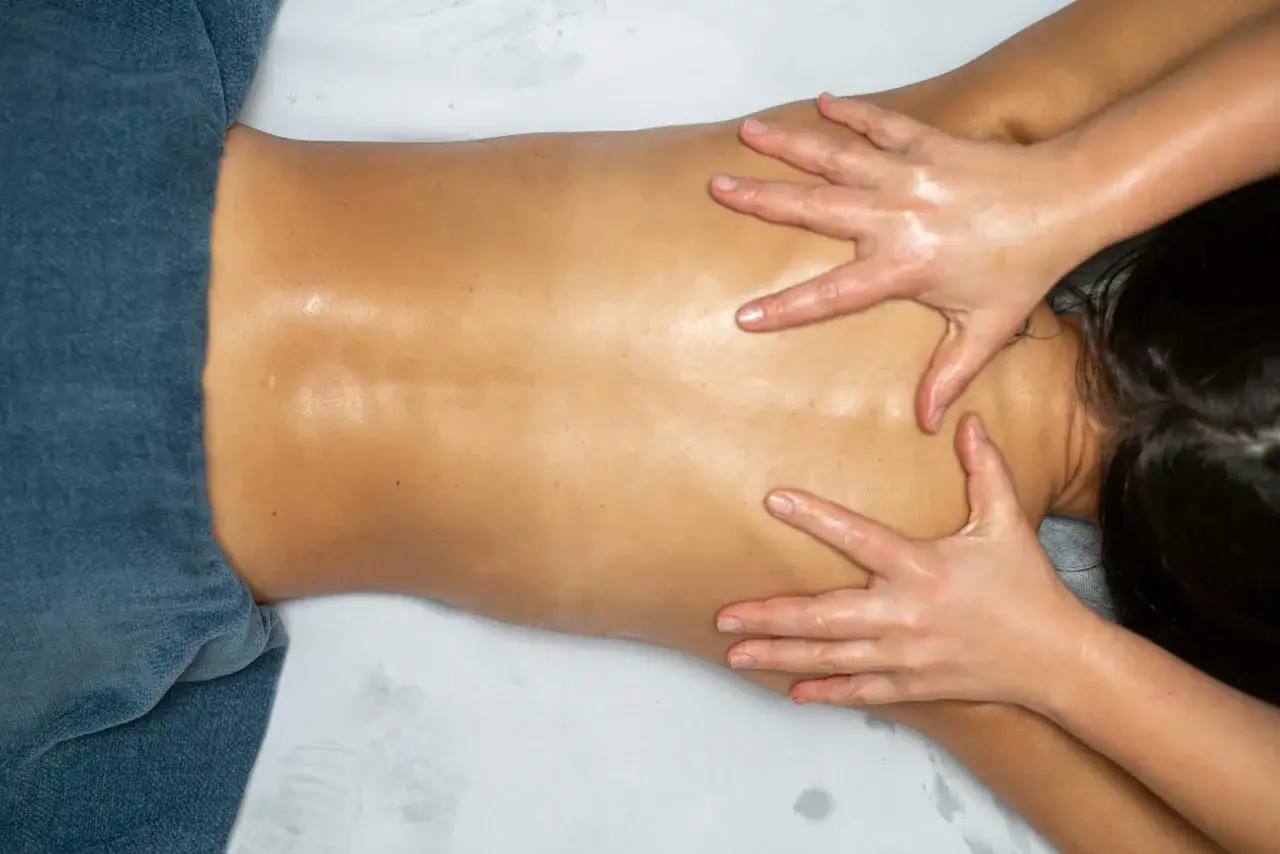 Mains expertes prodiguant un osteo massage relaxant sur le dos huil&eacute; d'une personne allong&eacute;e, soulageant les tensions musculaires.