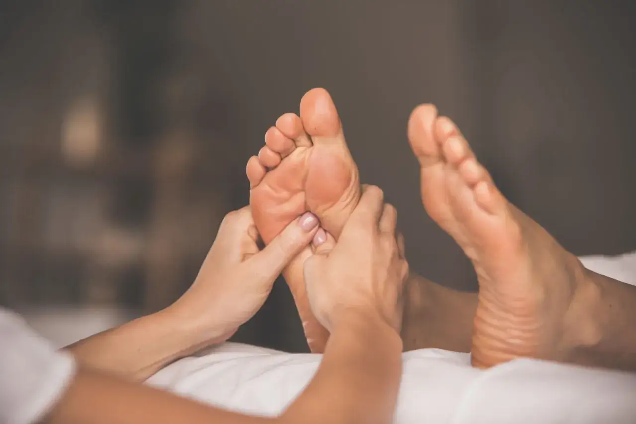 Mains massant un pied, une s&eacute;ance de r&eacute;flexologie plantaire pour soulager le stress.