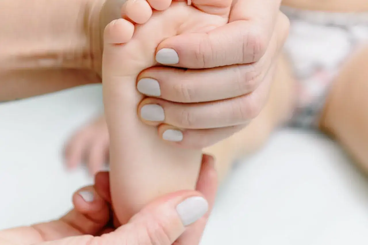 Mains douces prodiguant un massage du pied d'un bébé, un moment de tendresse et de bienfait massage.