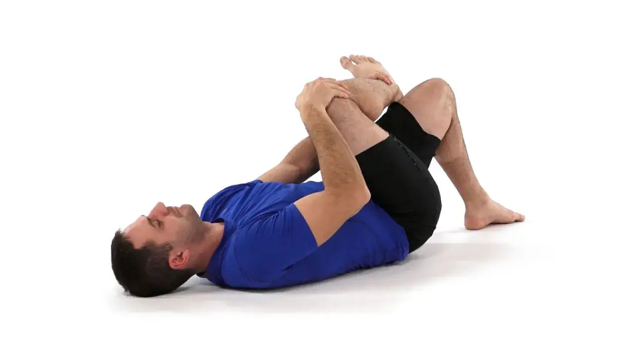 Homme en bleu, genou pli&eacute; sur la poitrine, pour un massage piriforme efficace.
