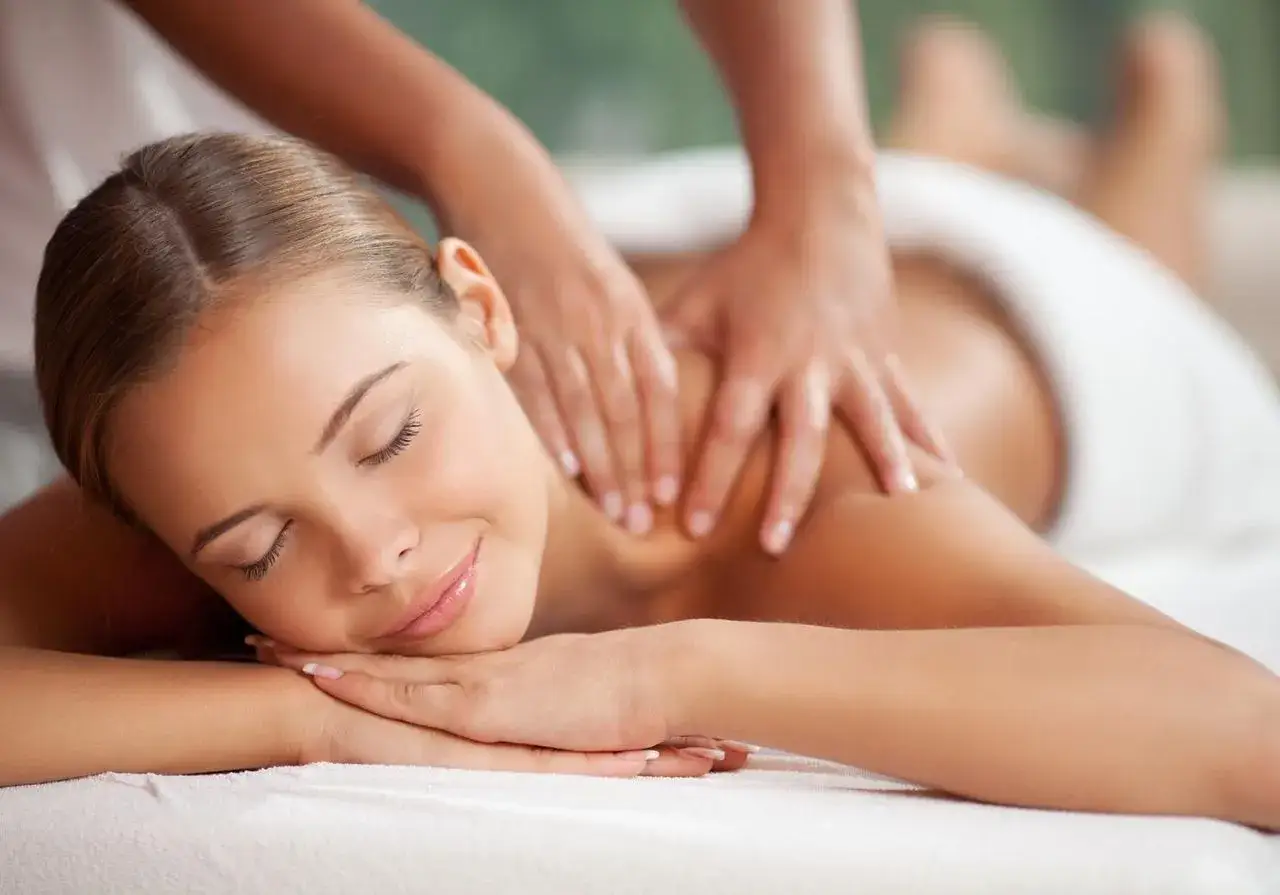 Une femme d&eacute;tendue re&ccedil;oit un massage chinois apaisant sur le dos. Ses yeux sont ferm&eacute;s, un sourire aux l&egrave;vres.