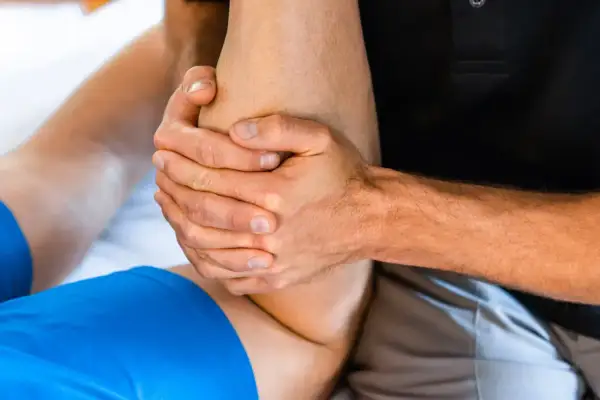 Mains expertes prodiguant un massage après sport sur une jambe. Soulagement musculaire garanti.