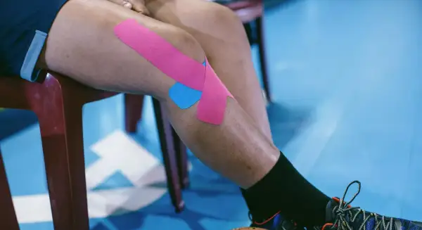 Jambe d'athlète avec un strap quadriceps rose et bleu, prêt pour l'action.