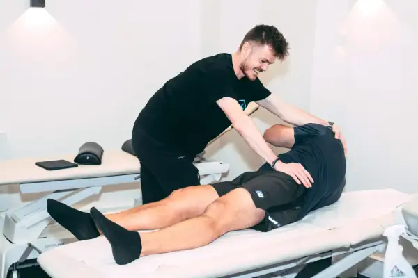 Un ostéopathe pratique un ostéo massage sur un patient allongé sur une table de soin, soulageant ses tensions musculaires.