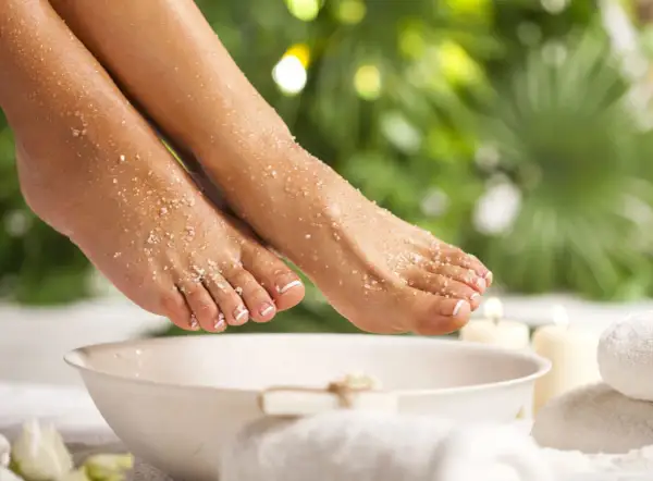 Pieds délicats recouverts de gros sel et de bicarbonate, prêts pour un bain de pied relaxant.