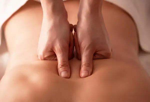 Mains expertes appliquant un massage profond sur le bas du dos pour soulager les tensions et favoriser la relaxation.
