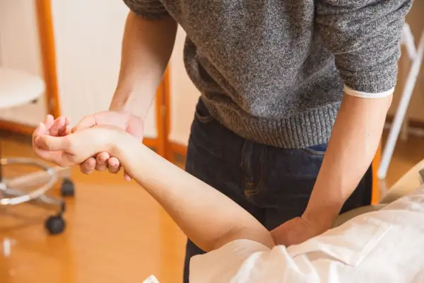Mains expertes prodiguant un massage du bras pour améliorer la circulation sanguine.